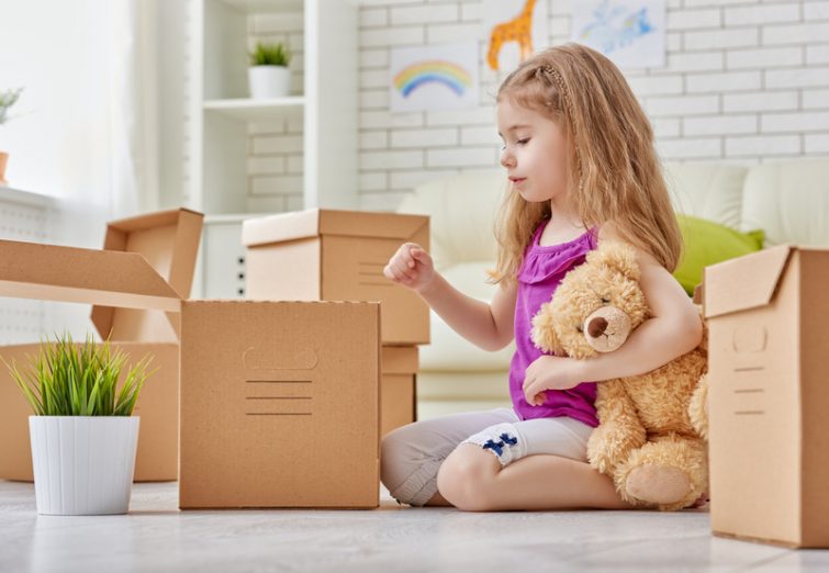 Umziehen mit Kindern – Mädchen hilft beim Packen der Umzugskartons