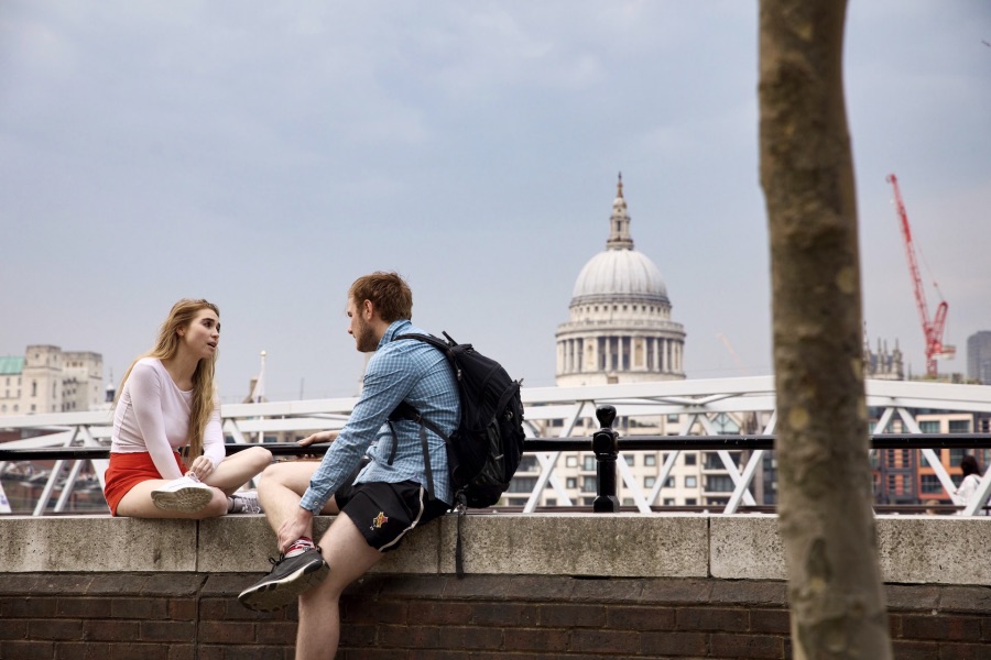 Entdecken Sie romantische Momente vor der ikonischen Kulisse der St. Paul's Cathedral in London. Dieses Bild zeigt ein junges Paar, das auf einer Mauer sitzt und die Aussicht auf die Stadt genießt, ideal für Reise- und Kulturliebhaber